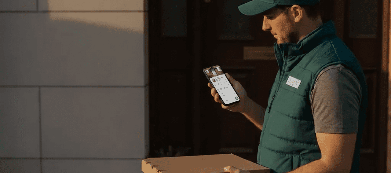 A delivery man holding a package, with the VayaPin mobile app open on his phone.