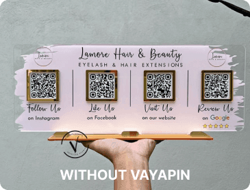 A hand holds a physical acrylic sign featuring four separate QR codes